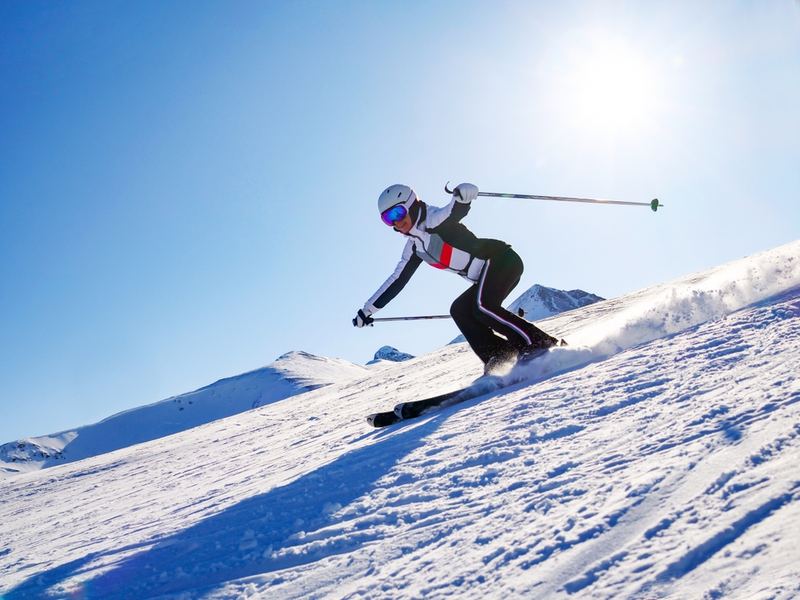 A skier carving a turn on a steep piste