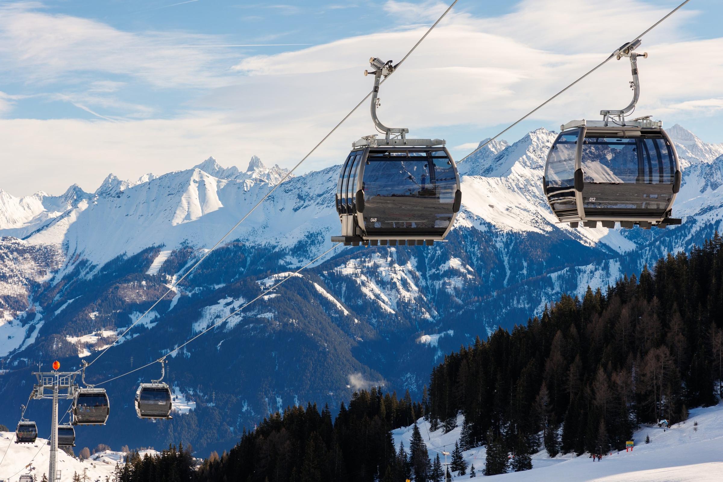 Gondola cabins over a snowy Alpine valley