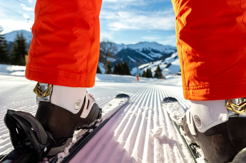 Close-up of ski boots clipped into skis on a freshly groomed piste